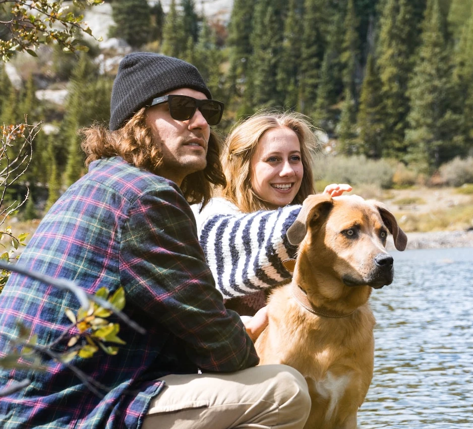 férfi és nő a víz mellett a kutyájukkal