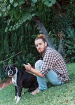 fiatal férfi a fűben ül a kutyájával